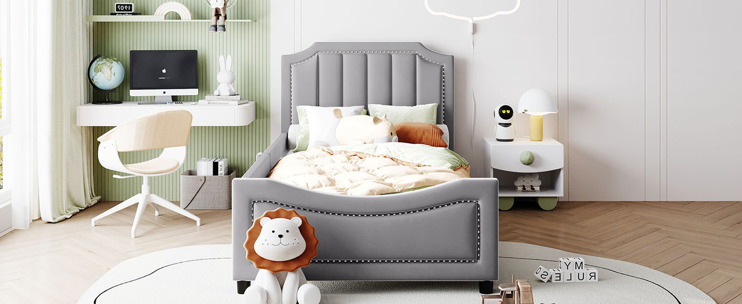 Gray upholstered twin bed with studded headboard and footboard