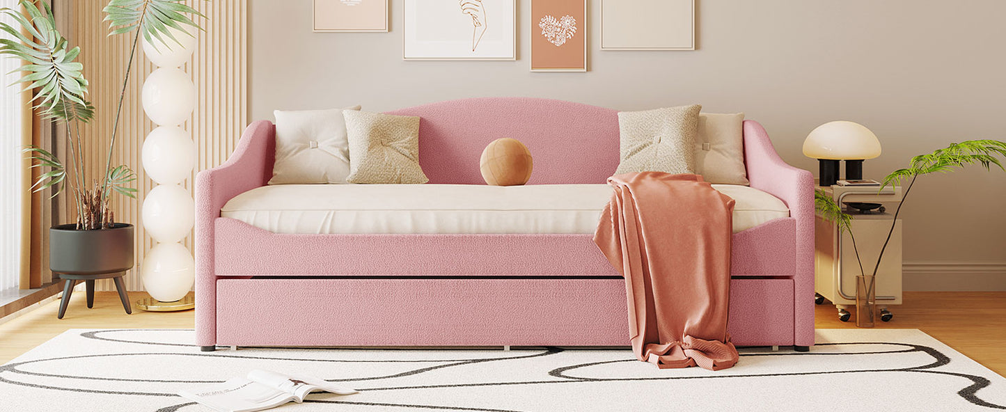 Pink upholstered daybed with pullout trundle and decorative pillows for modern living space