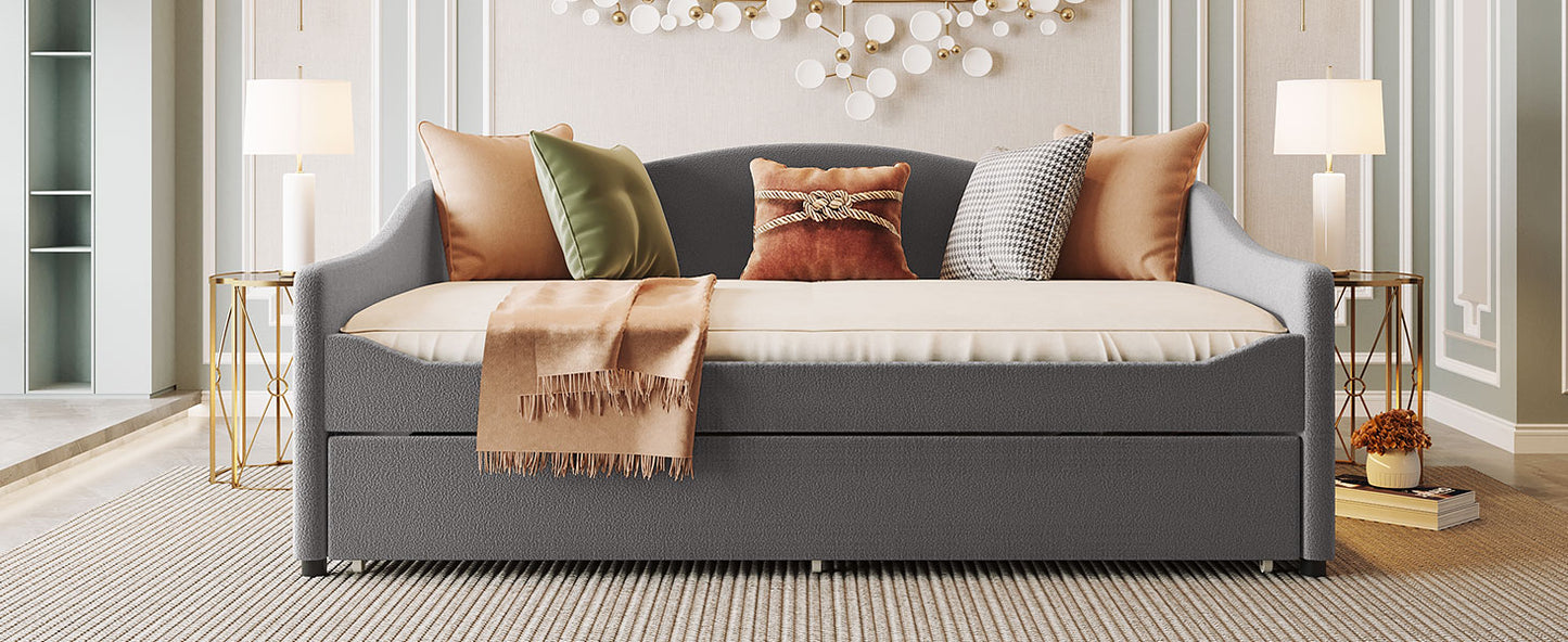 Dark gray upholstered daybed with pullout trundle and decorative pillows
