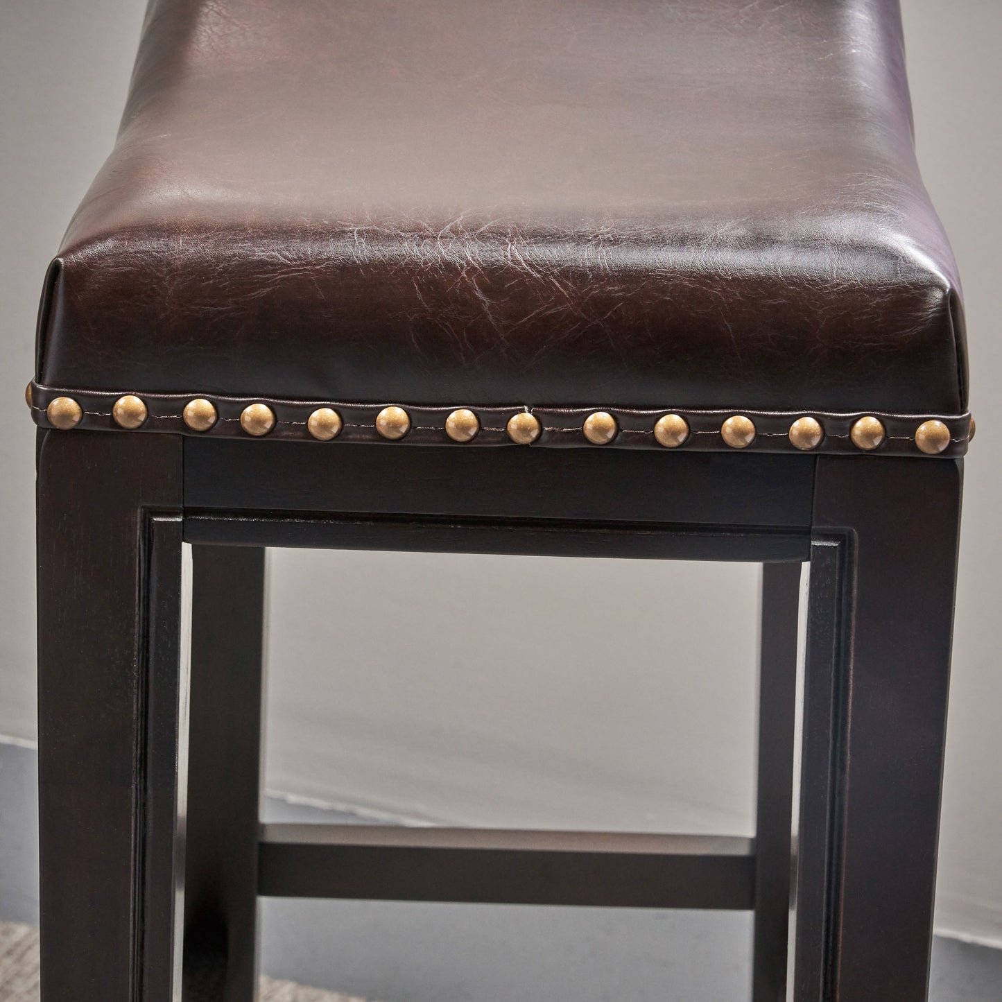 Dark brown faux leather bar stool with brass nailhead trim