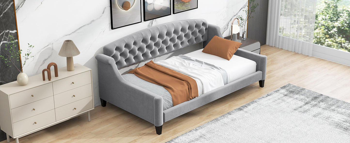 Grey velvet daybed with tufted headboard and diamond stitching featuring a warm throw blanket