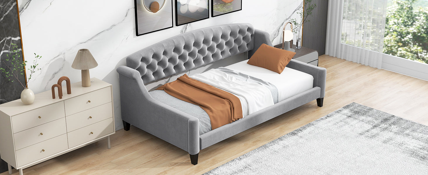 Grey velvet daybed with tufted headboard and diamond stitching featuring a warm throw blanket