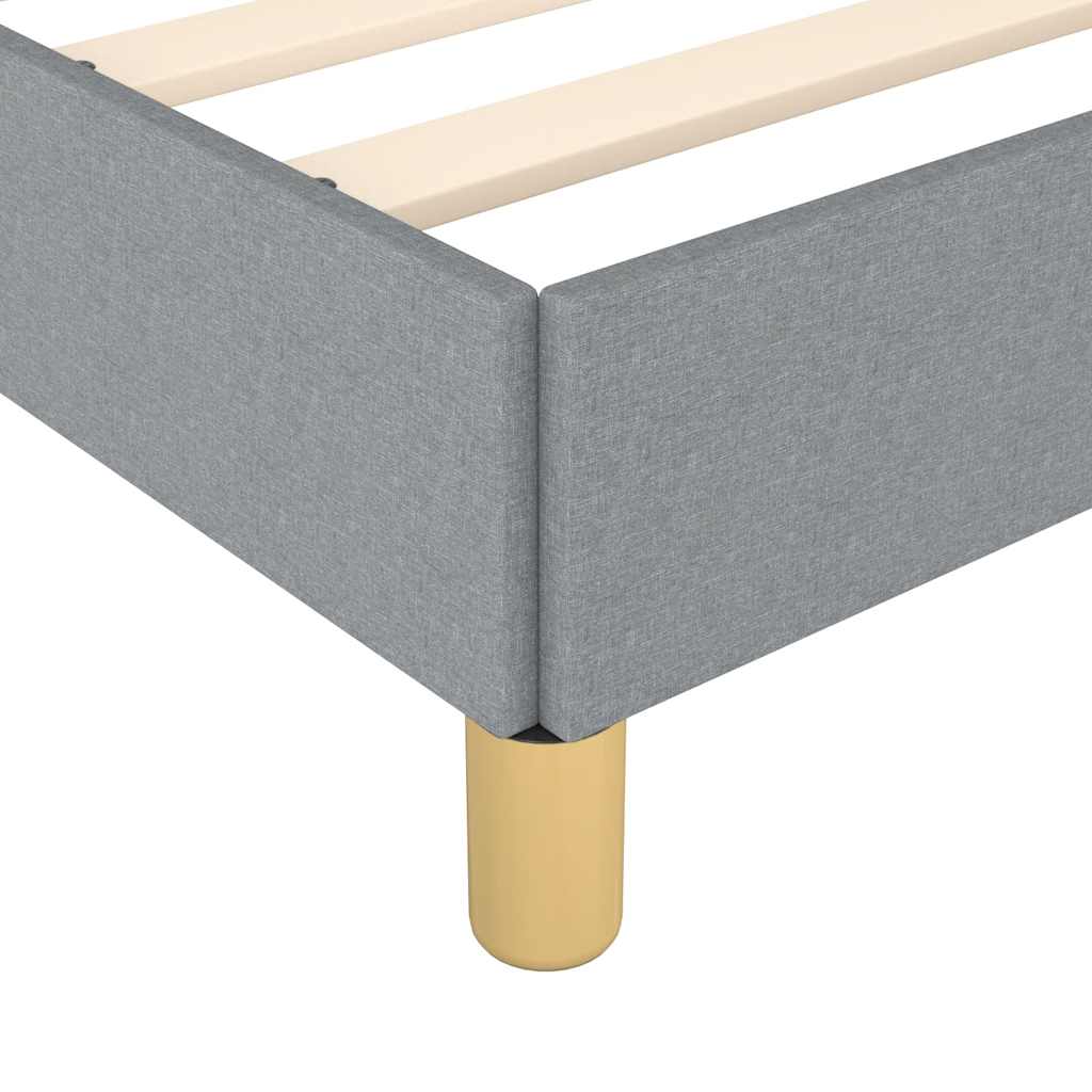 Closeup of a grey upholstered bed frame with a gold leg