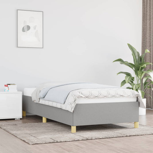 Gray upholstered twin bed frame with wooden legs on a light rug