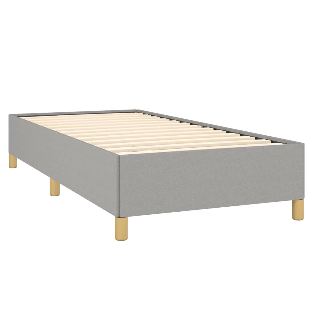 Gray upholstered twin bed with wooden legs and white bedding