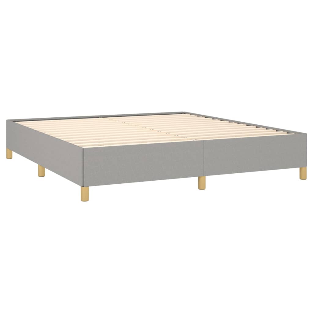 Grey upholstered queen bed frame with wooden legs and quilted blanket