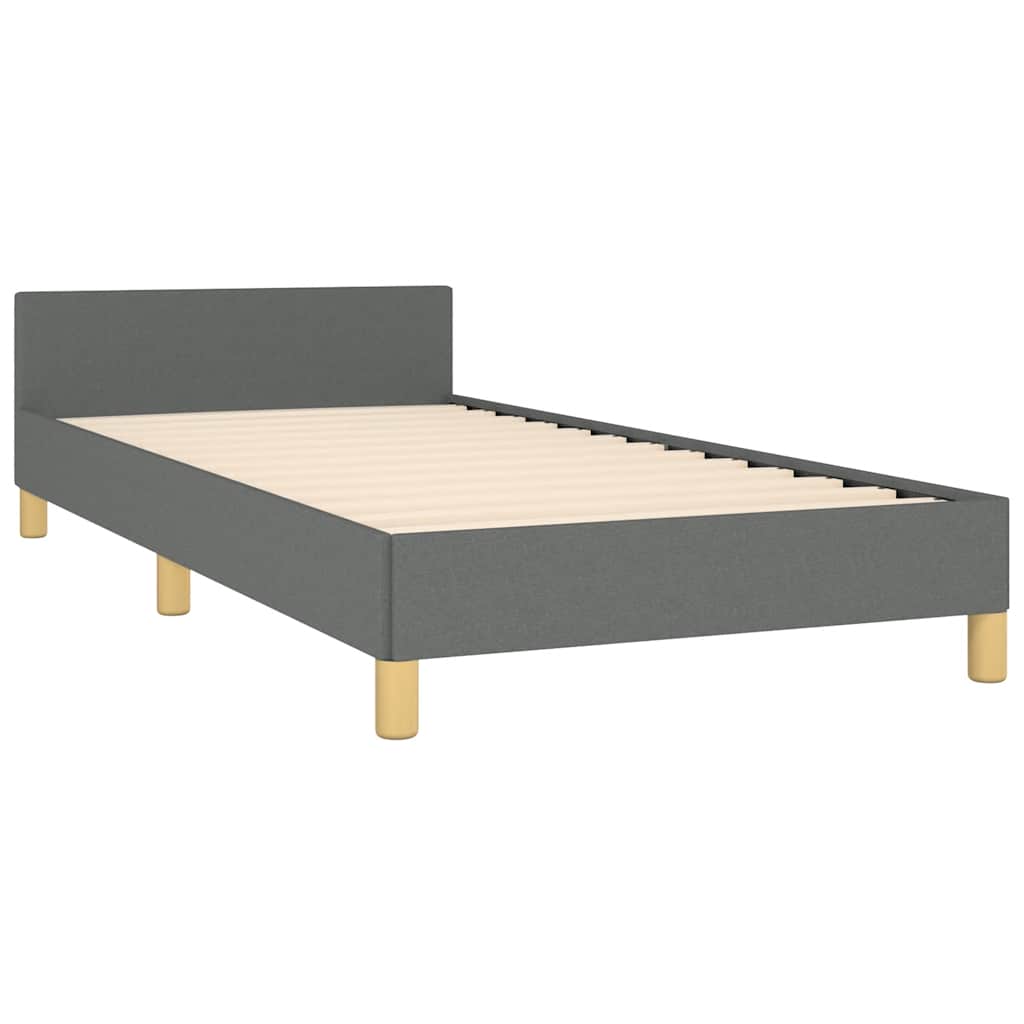 Dark grey upholstered bed frame with natural wood legs neatly made with white and grey linens