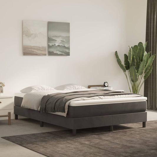 Dark grey upholstered bed frame with a white mattress and grey throw blanket