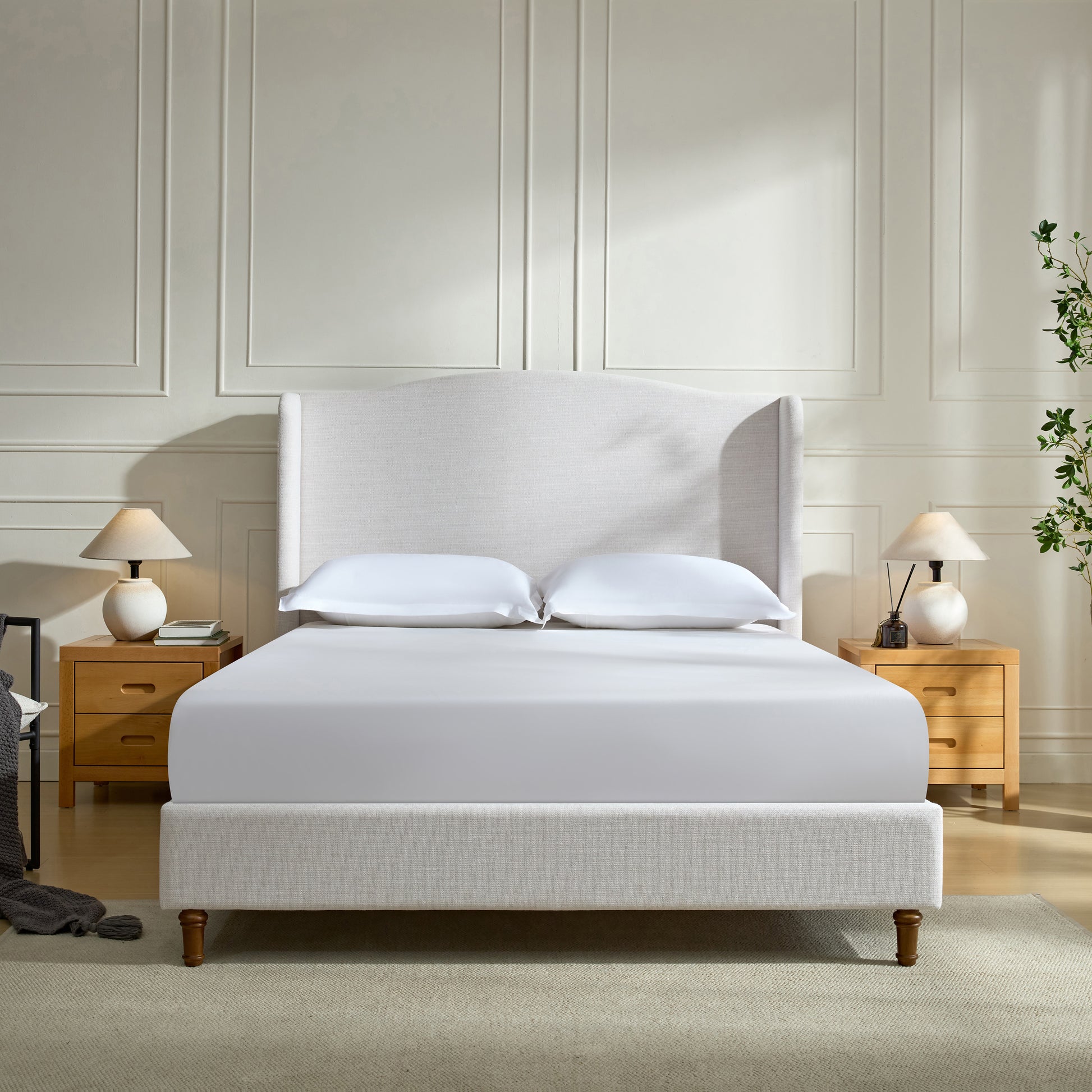 Cream linen wingback bed with white bedding and wooden nightstands