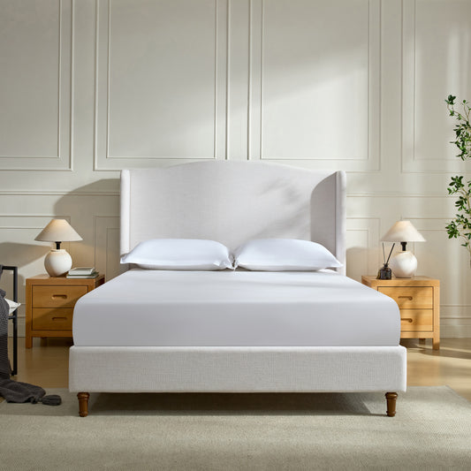 Cream linen wingback bed with white bedding and wooden nightstands