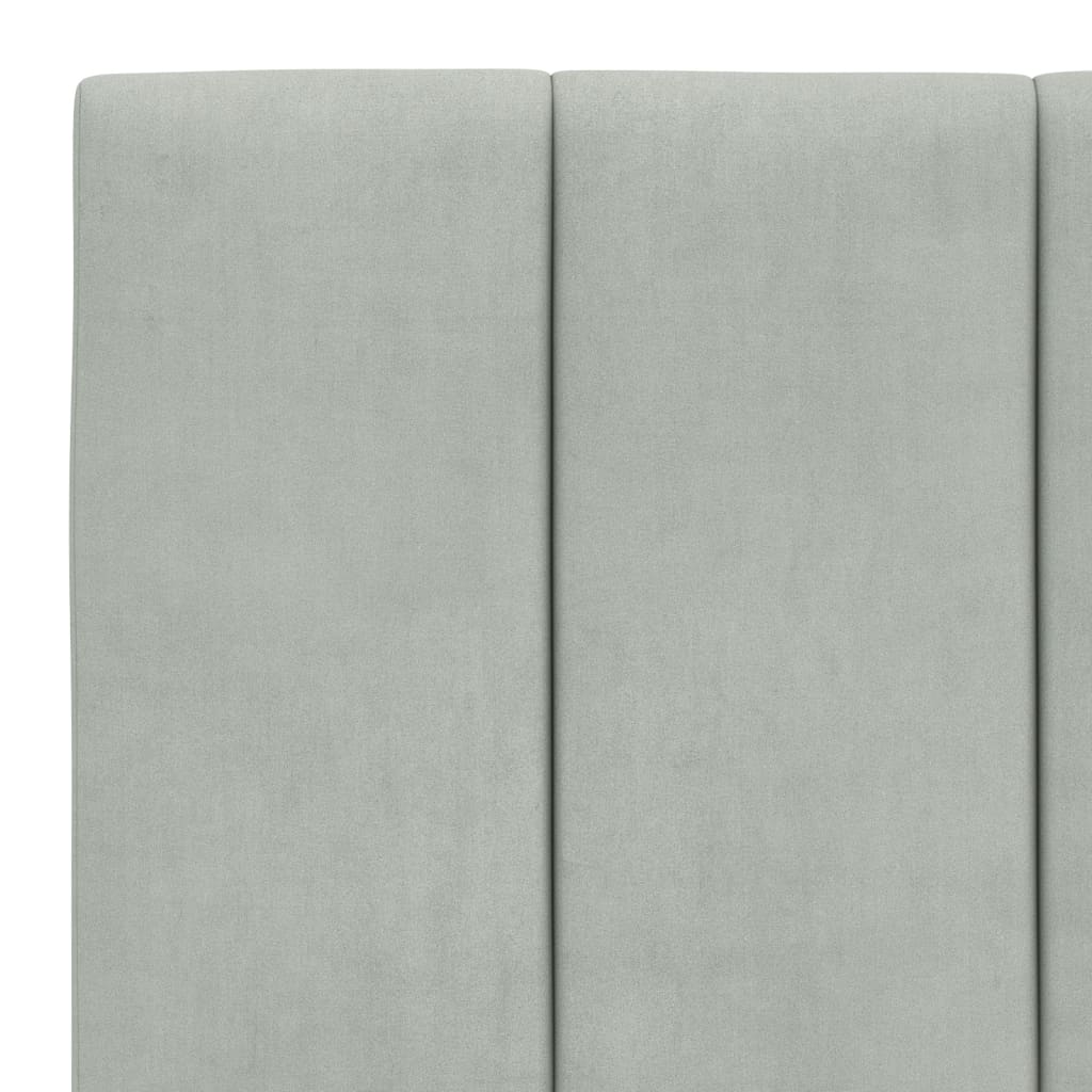 Closeup of a light gray upholstered bed frame corner with a black cylindrical leg