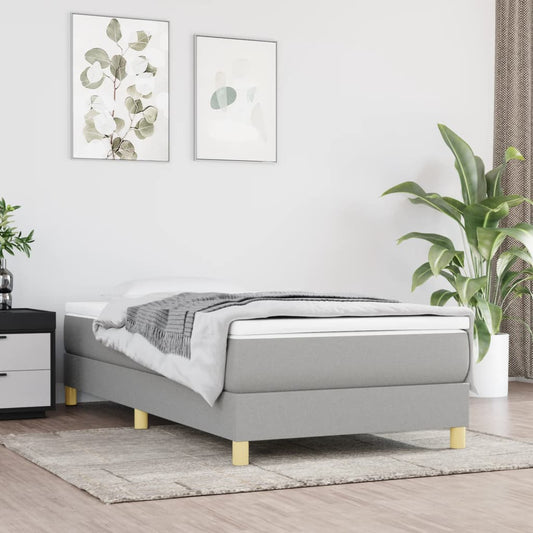 Modern grey upholstered twin bed frame with white mattress and blanket