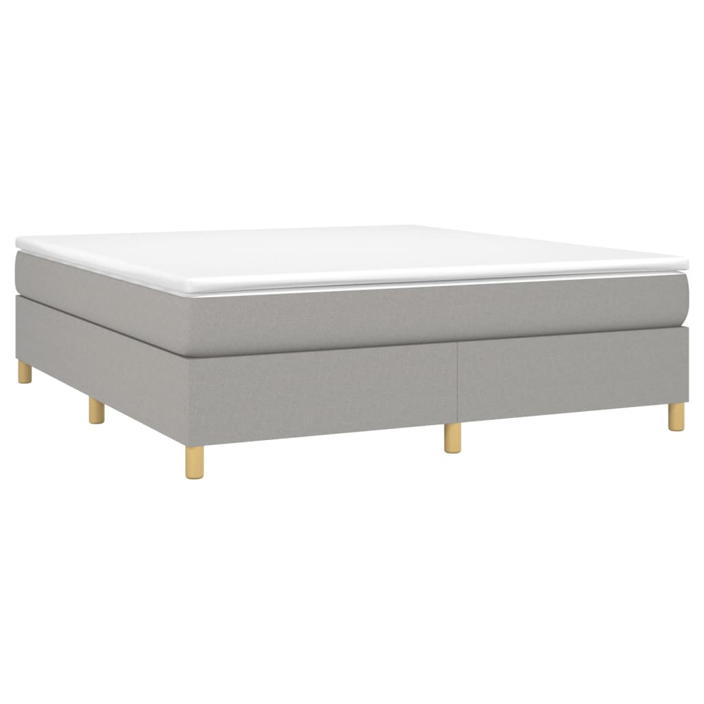 Grey upholstered divan bed base with a white mattress topper and wooden legs