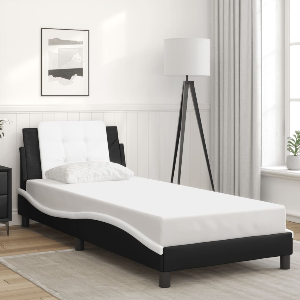 Black and white upholstered chaise lounge with tufted headboard and wooden slats
