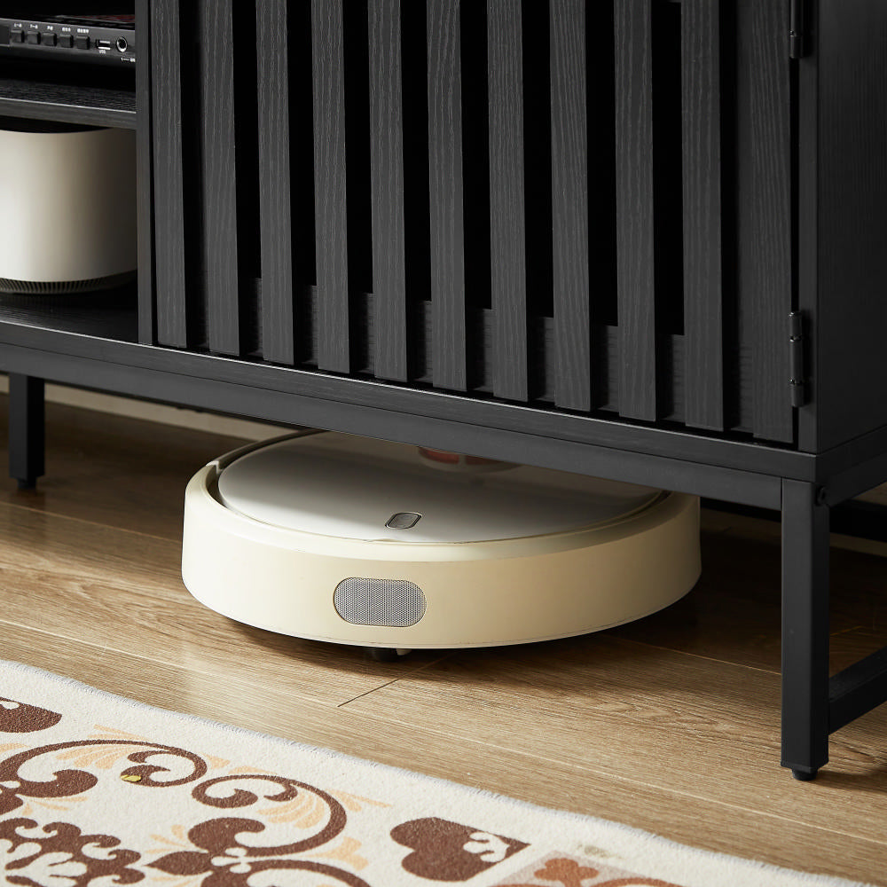 Cream colored robot vacuum cleaning under black slatted media console
