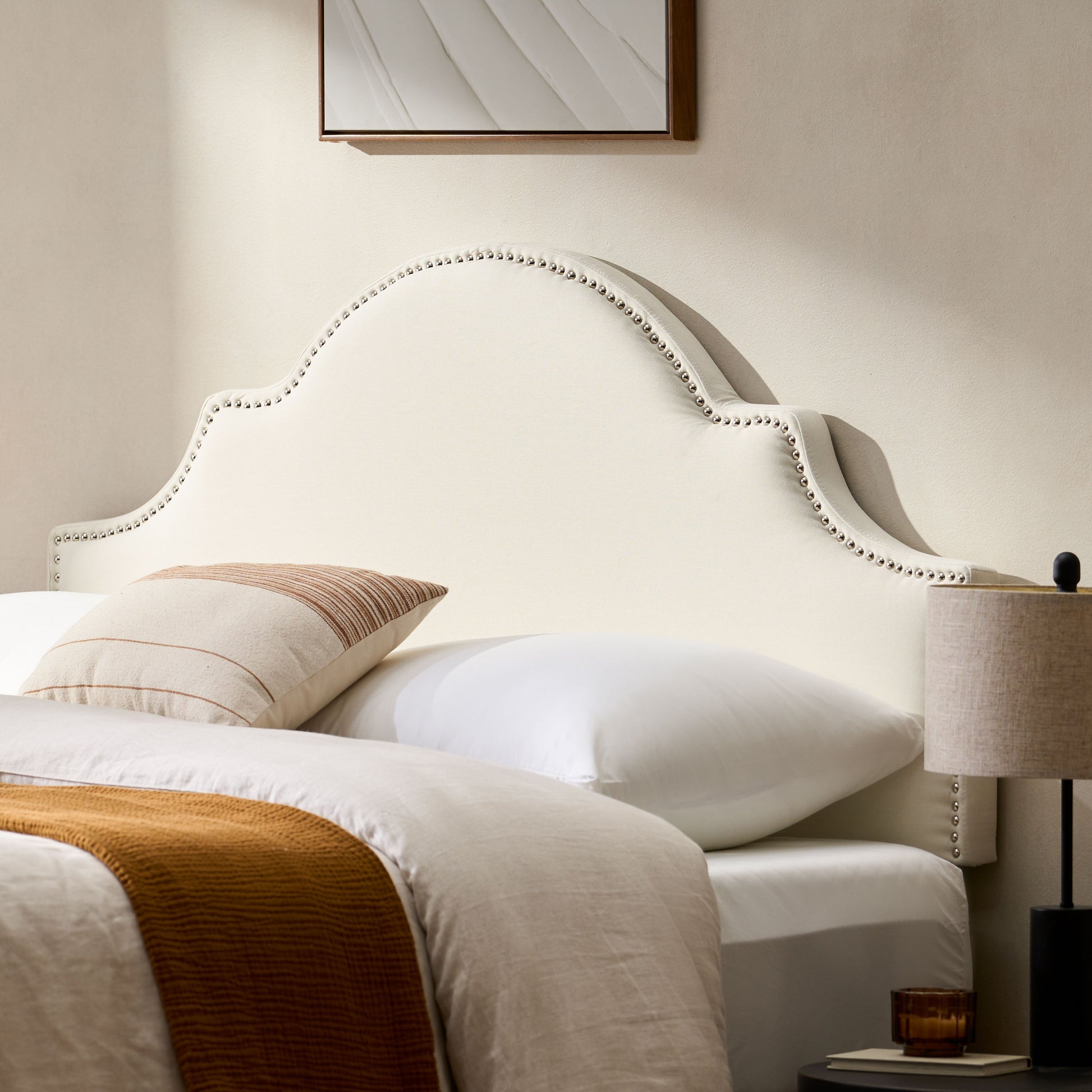 Elegant cream upholstered headboard with silver nailhead trim and scalloped edge