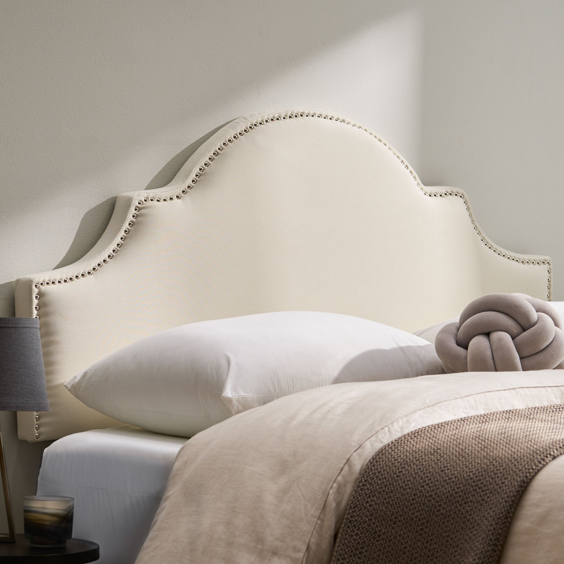 Cream upholstered headboard with silver nailhead trim