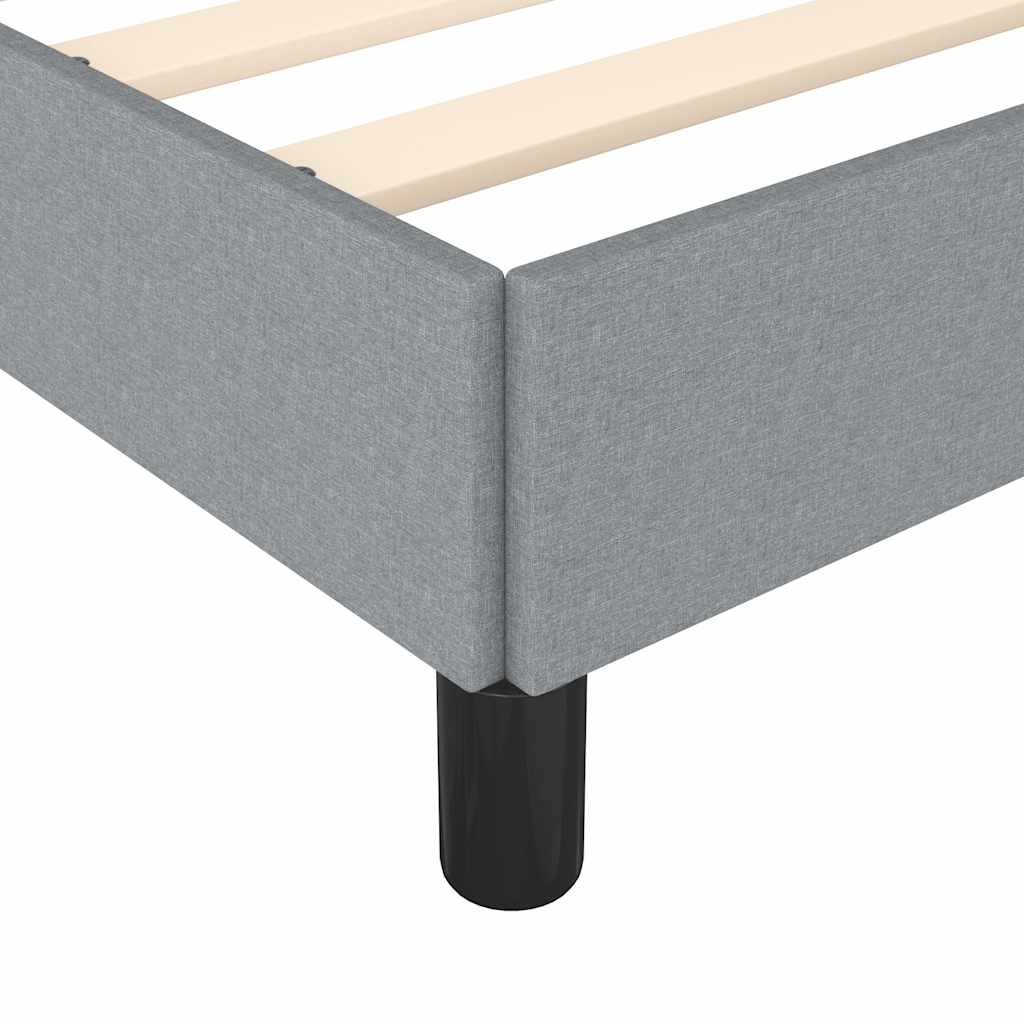 Closeup of a grey upholstered bed frame with wooden slats and a black leg