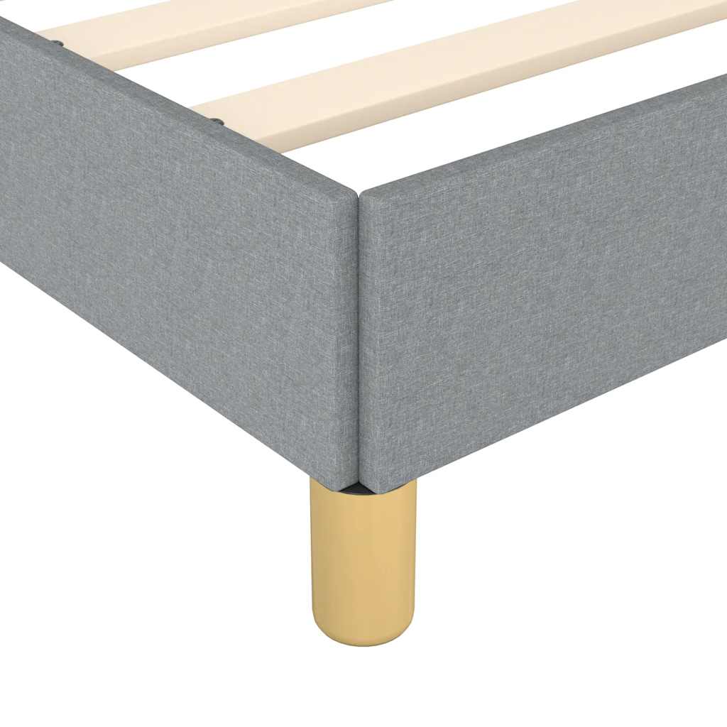 Closeup of a grey upholstered bed frame with wooden slats and a gold metal leg