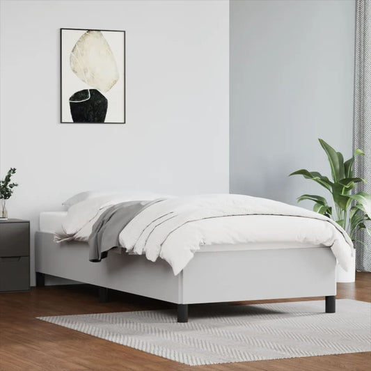 Modern white upholstered single bed frame with grey throw blanket