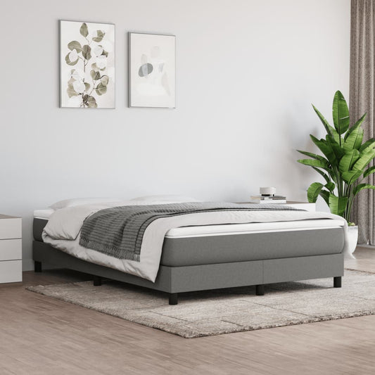 Grey upholstered divan bed base with white mattress and charcoal throw