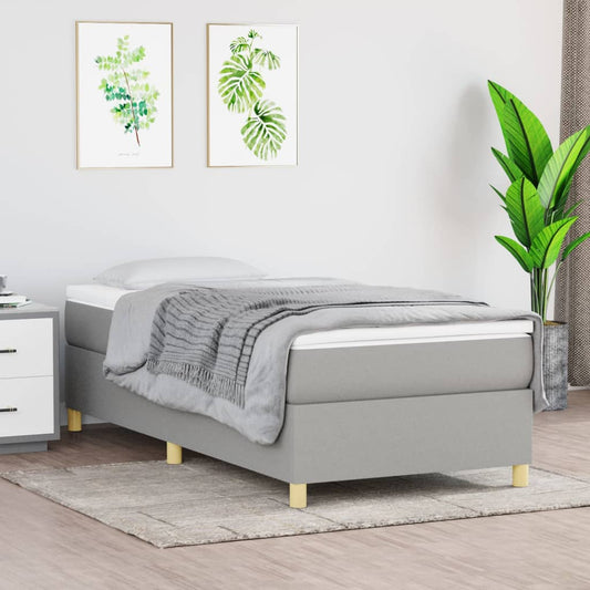 Gray upholstered divan bed with white mattress and wooden legs