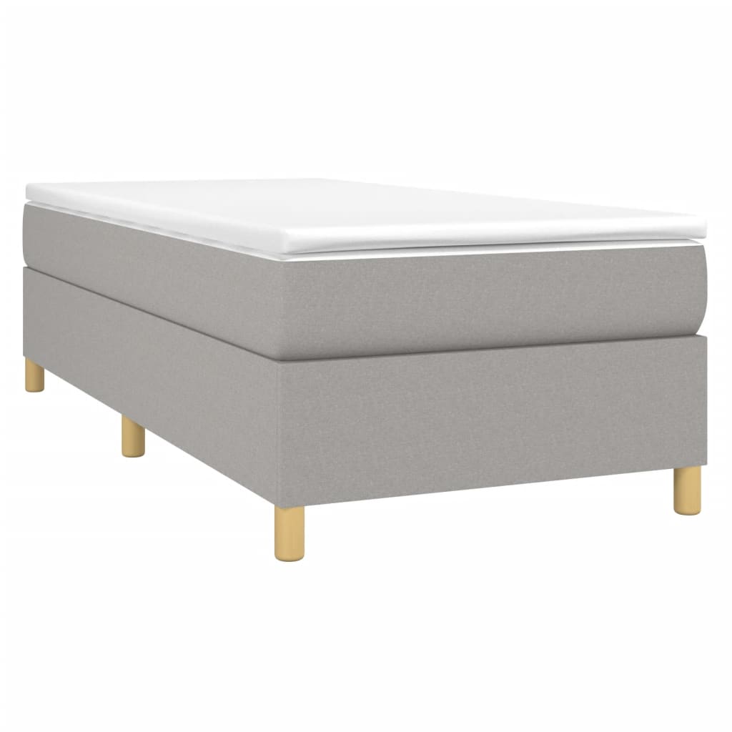 Grey upholstered divan bed with white mattress topper and wooden legs