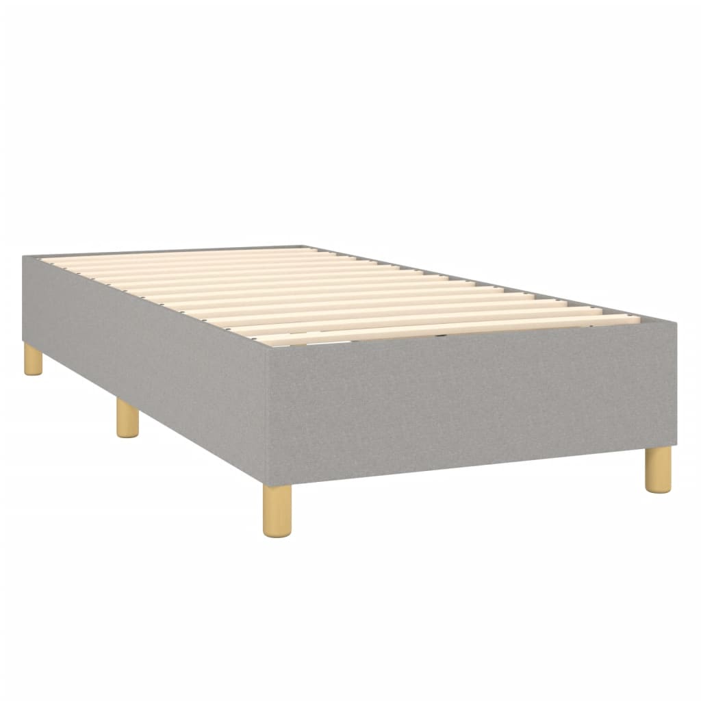 Grey upholstered divan bed with a white mattress topper and wooden legs