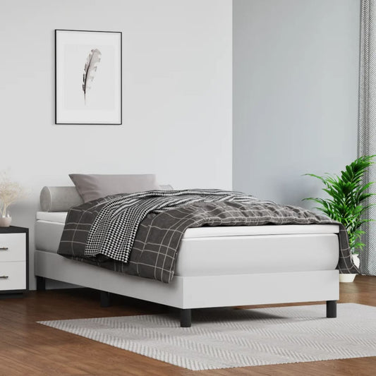 White upholstered twin bed frame with a grey patterned duvet and lumbar pillow