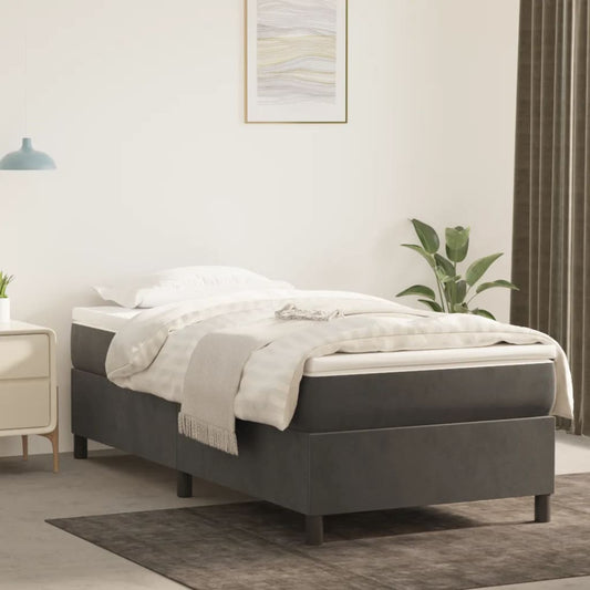 Dark grey upholstered single bed frame with a white mattress and striped duvet