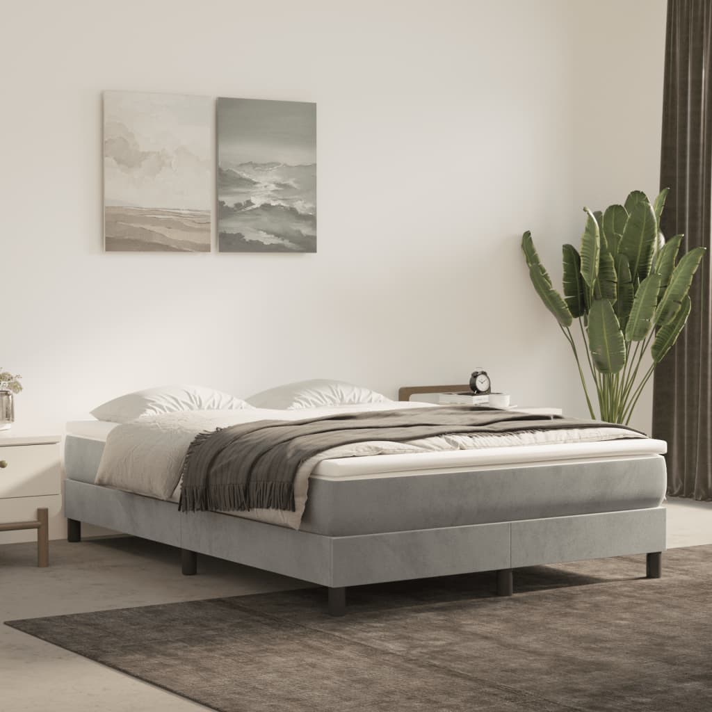 Grey upholstered bed frame with white bedding and a grey throw blanket