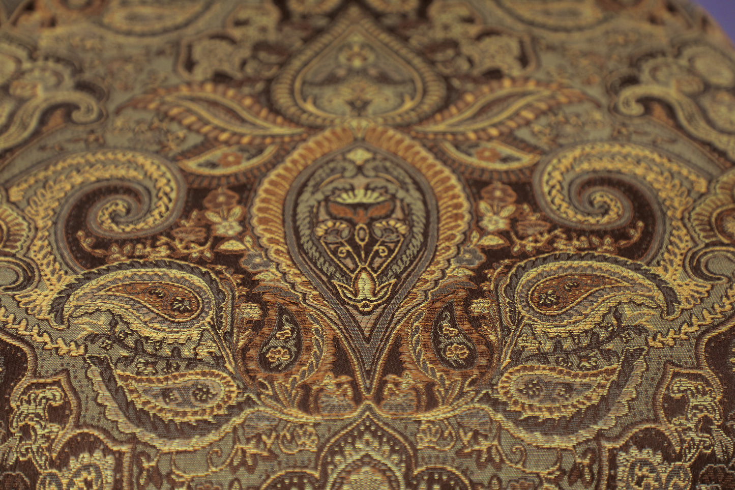 Detailed view of a tapestry fabric with a rich paisley pattern in gold and brown tones