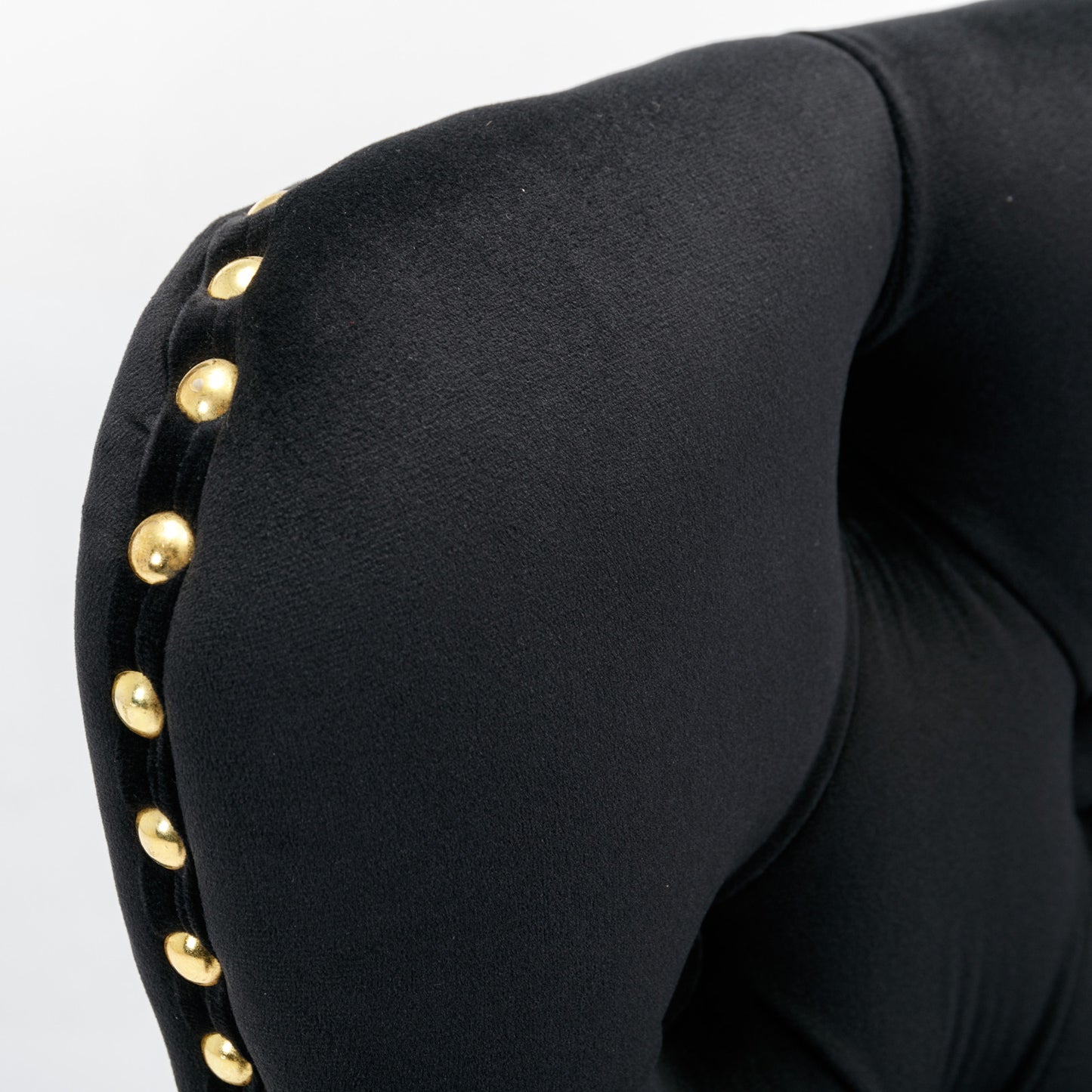 Black velvet armchair detail with gold stud accents