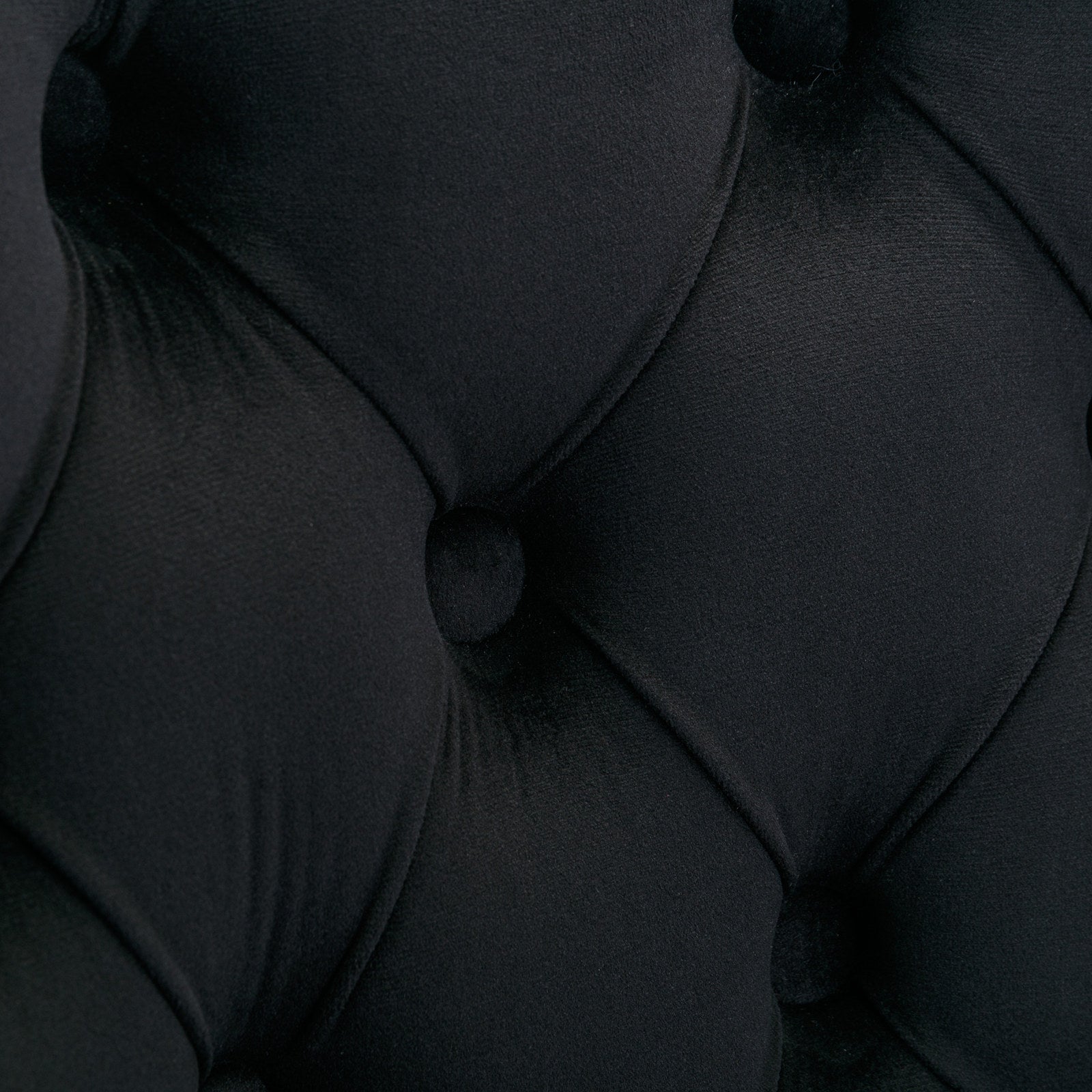 Closeup of tufted black velvet fabric with deep diamond pattern