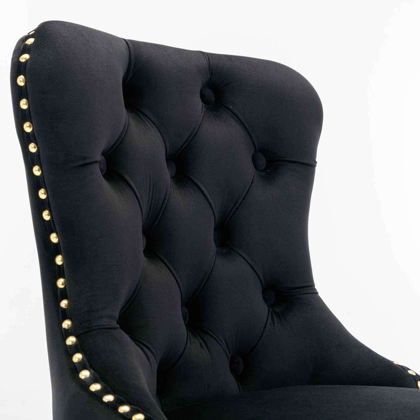 Black velvet armchair with tufted back and gold nailhead trim accents