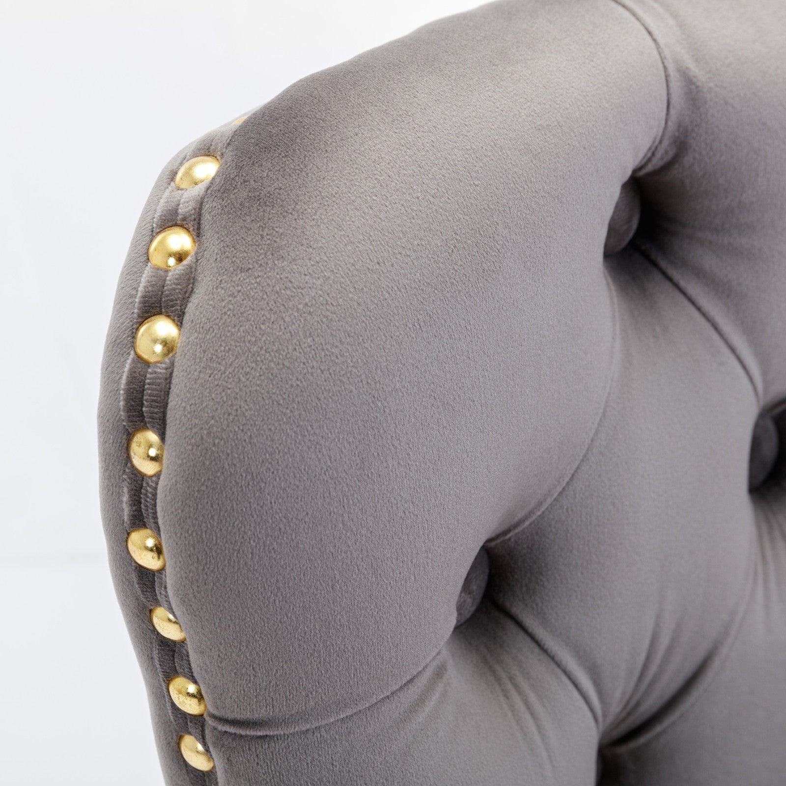 Grey velvet armchair with gold nailhead trim detailing on the armrest