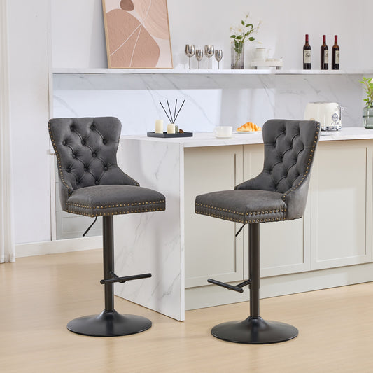 Two grey tufted leatherette bar stools with gold nailhead trim adjustable height