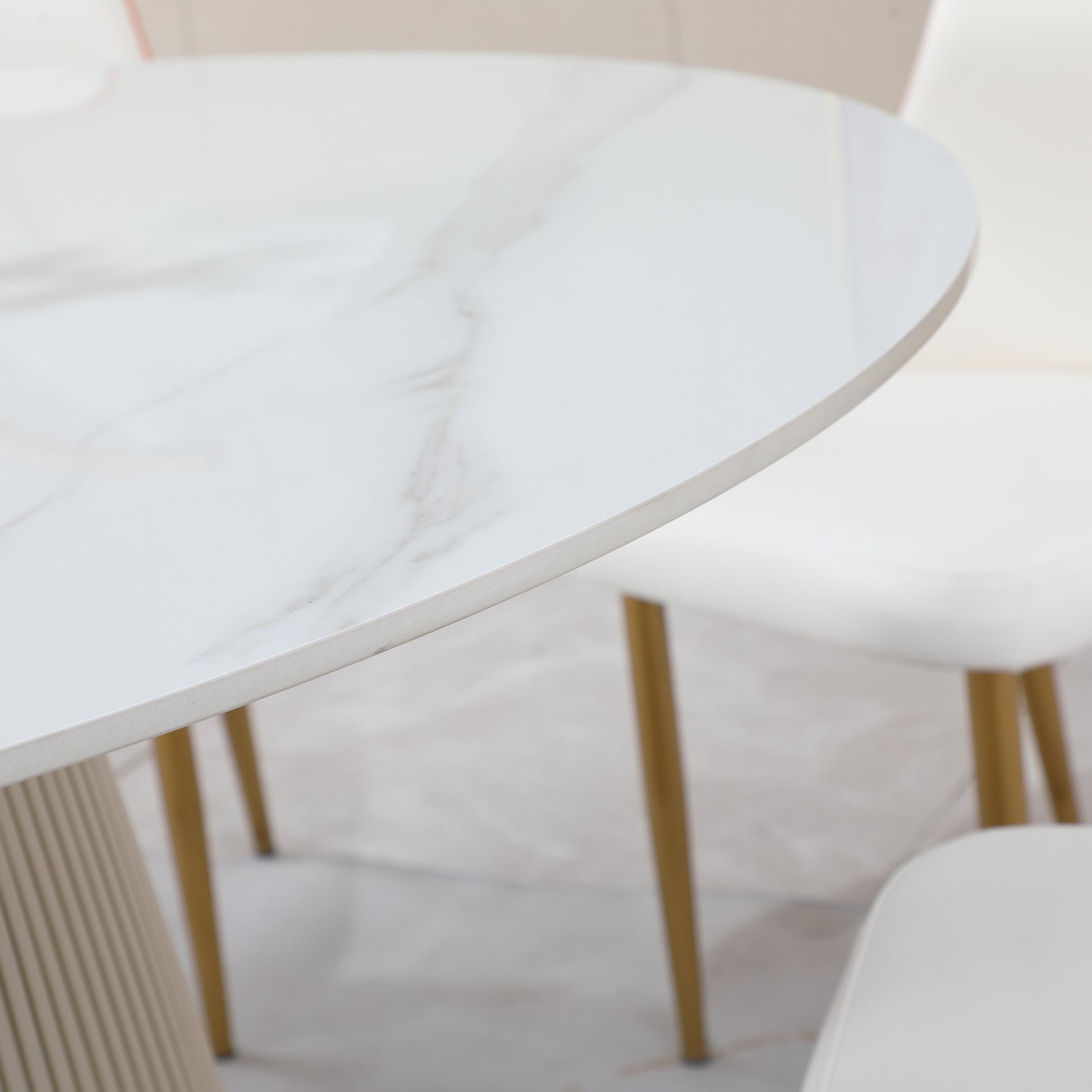 White marble dining table with gold legs and fluted pedestal base