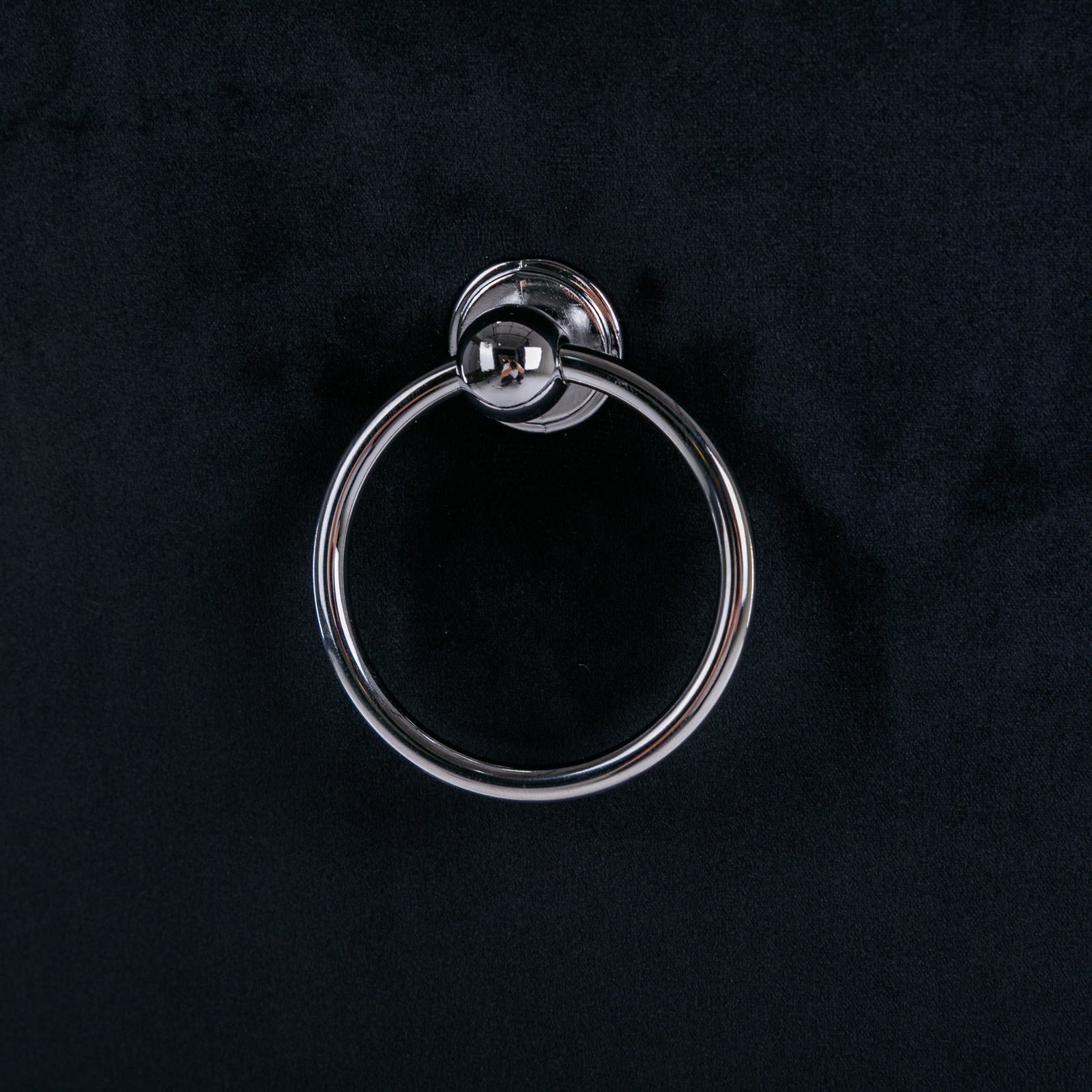 Silver ring drawer pull on a black cabinet door