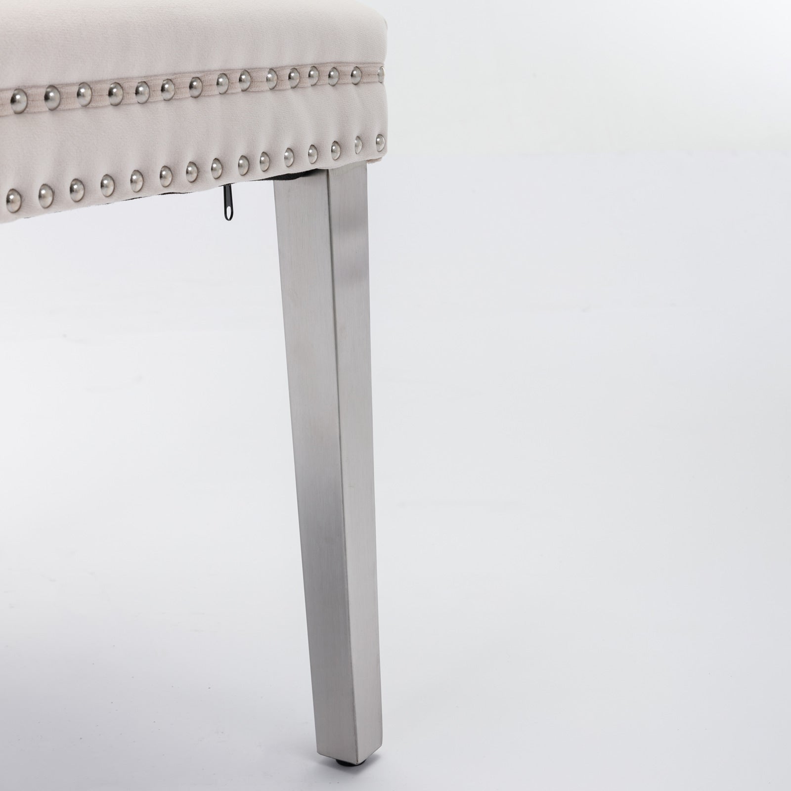 Beige upholstered chair detail with silver nailhead trim and brushed nickel leg
