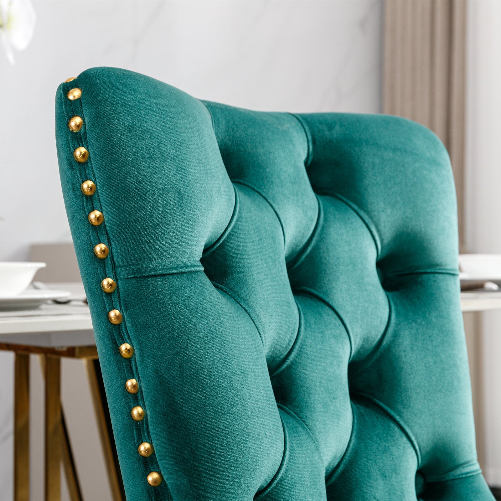 Teal velvet dining chair with tufted back and gold nailhead trim
