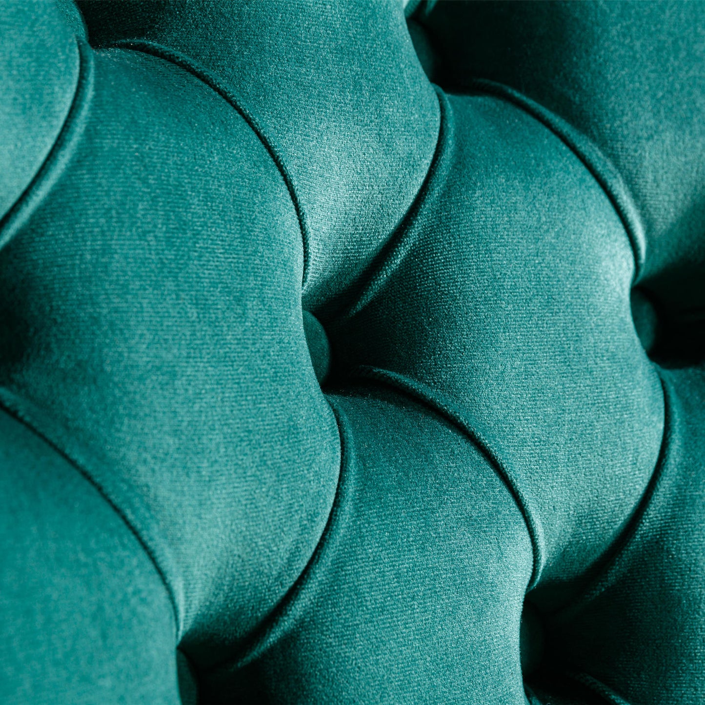 Teal velvet tufted upholstery detail showing deep button accents and plush texture