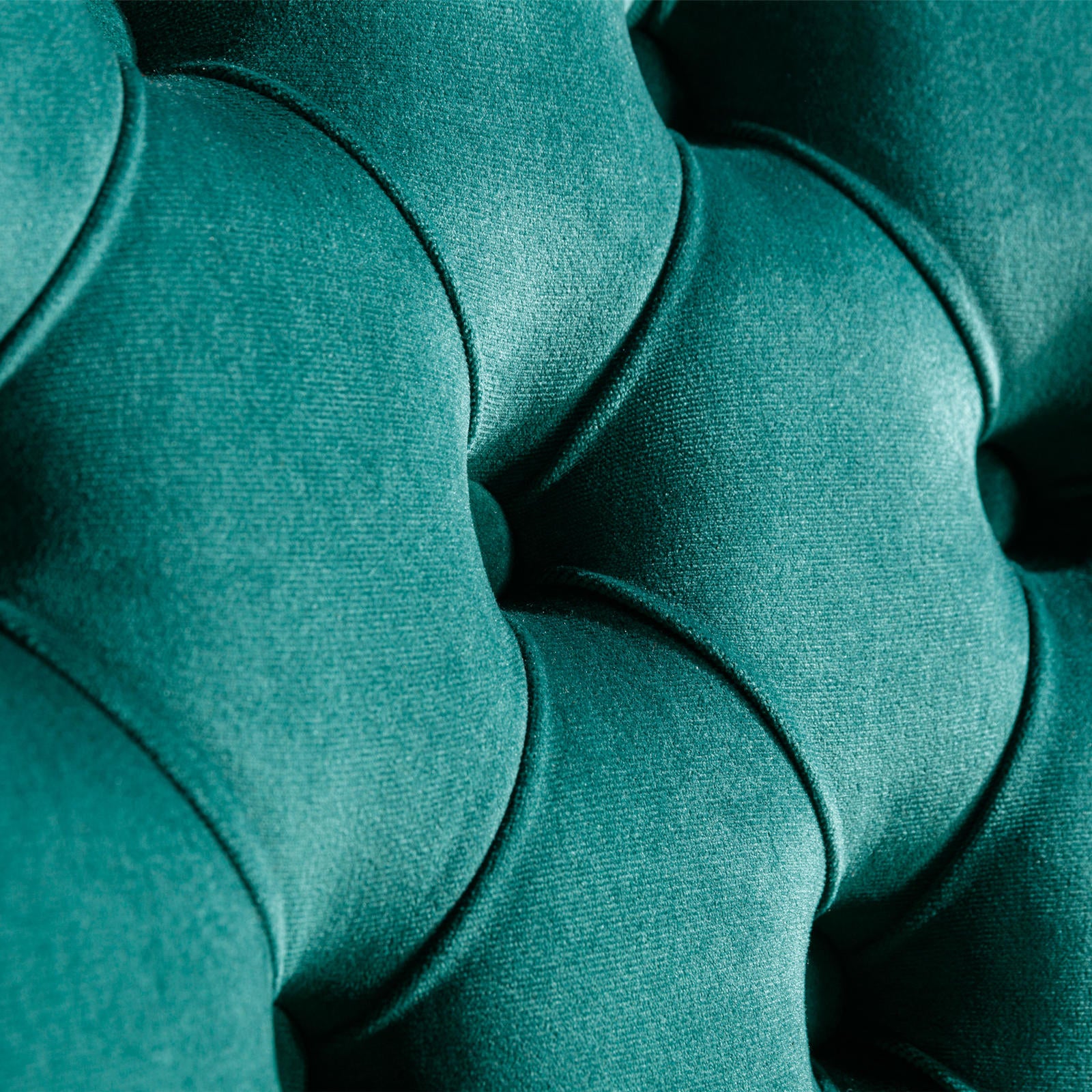 Teal velvet tufted upholstery detail showing deep button accents and plush texture