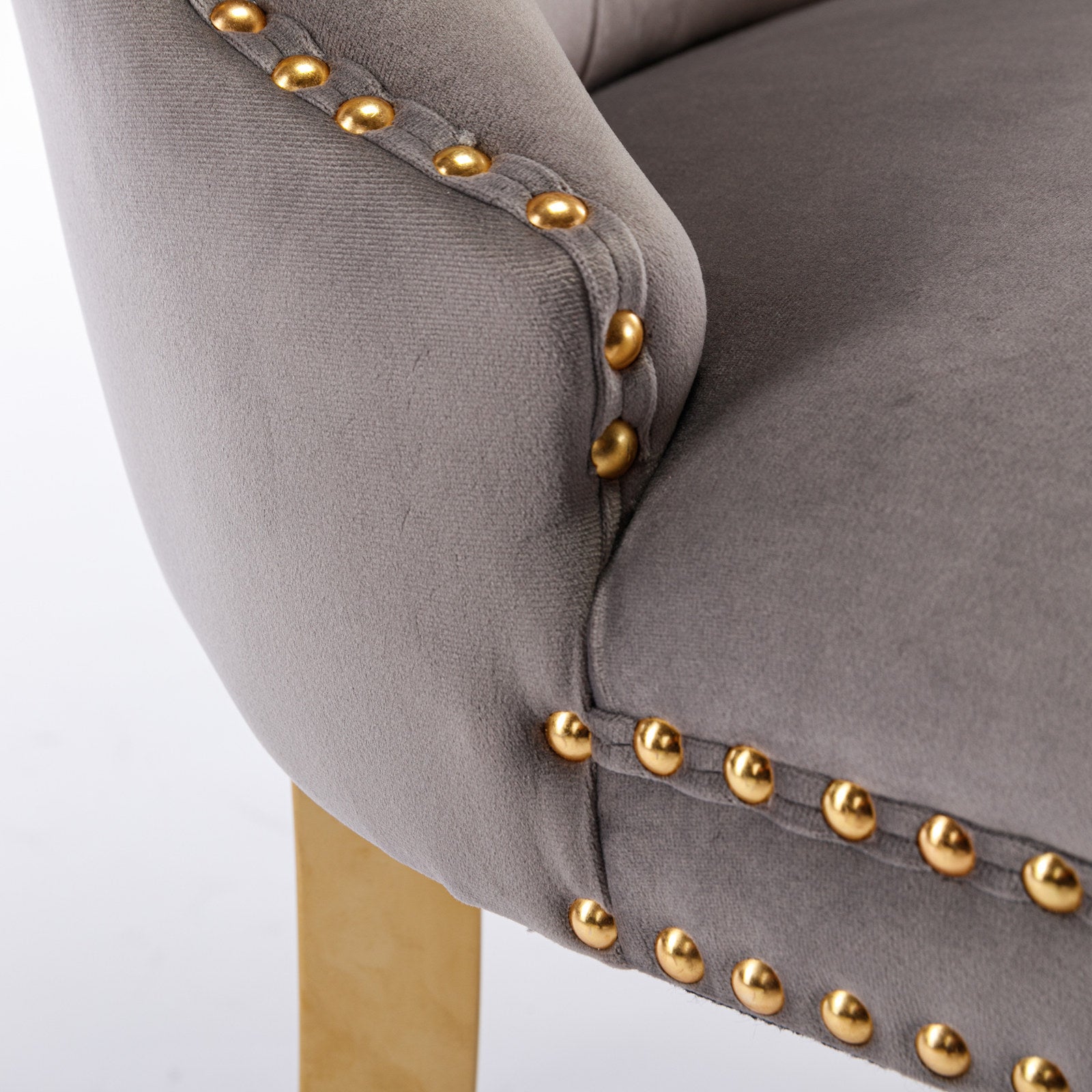 Closeup of gray velvet accent chair with gold nailhead trim detail and gold metal leg