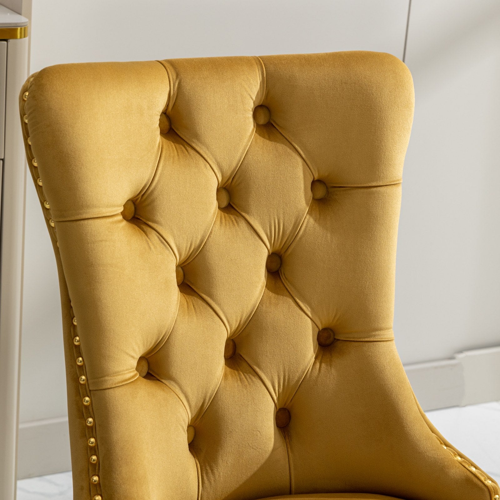 Tufted mustard velvet dining chair with gold nailhead trim