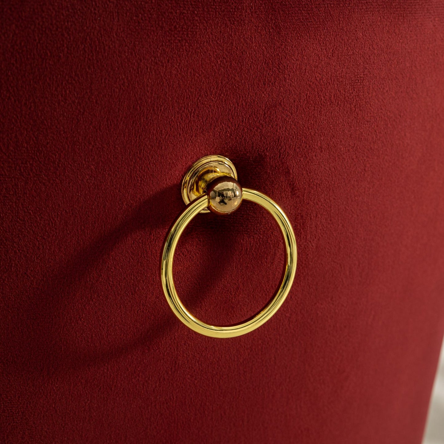 Red velvet chair detail with a gold ring pull handle