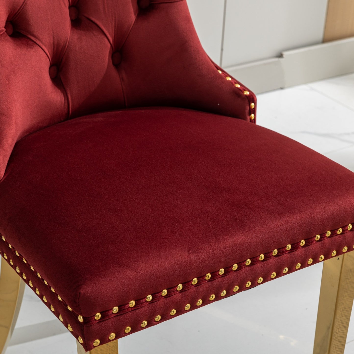 Deep red velvet accent chair with gold nailhead trim