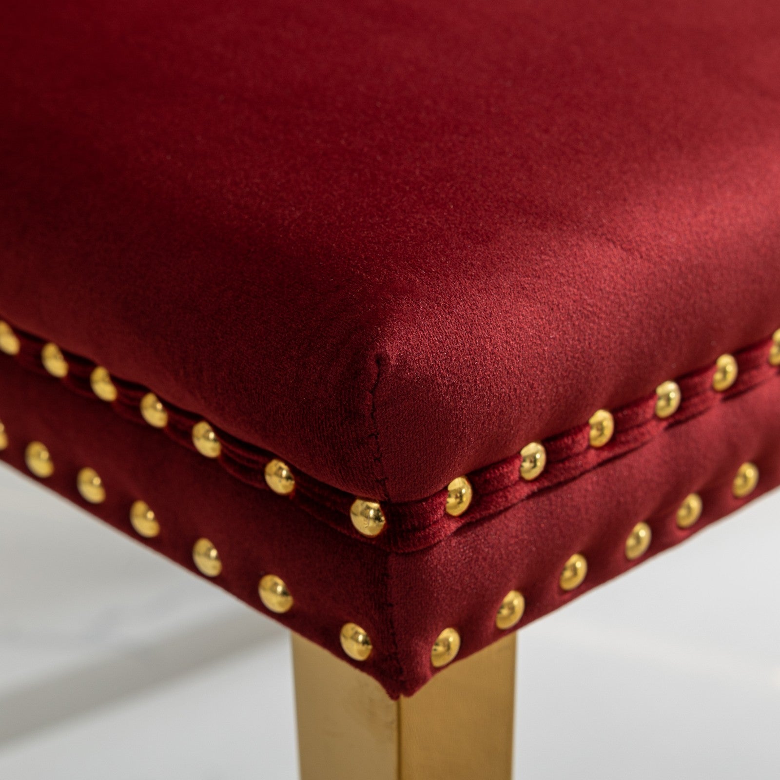 Red velvet accent chair with brass nailhead trim and gold legs