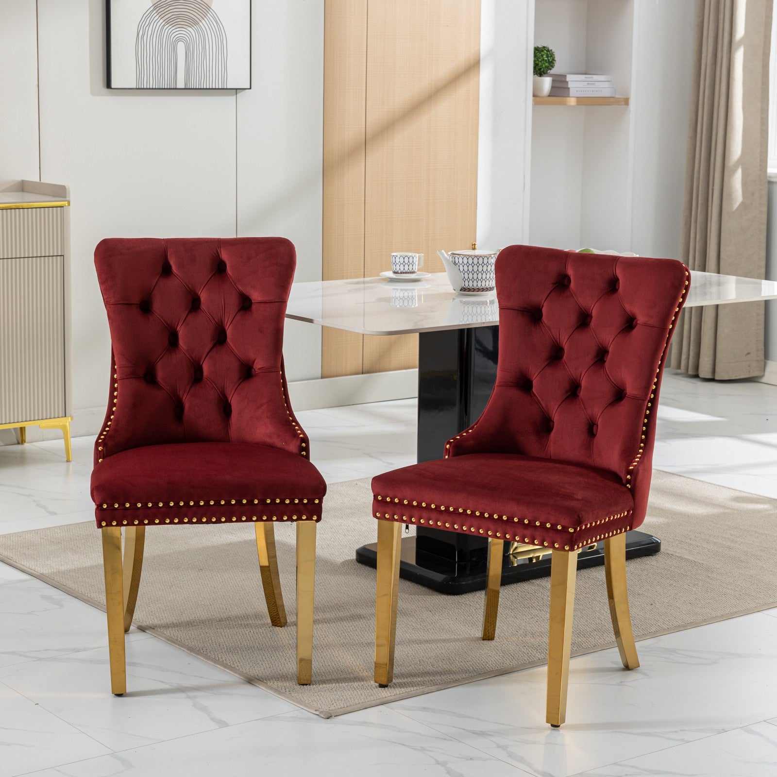 Two tufted burgundy velvet dining chairs with gold legs