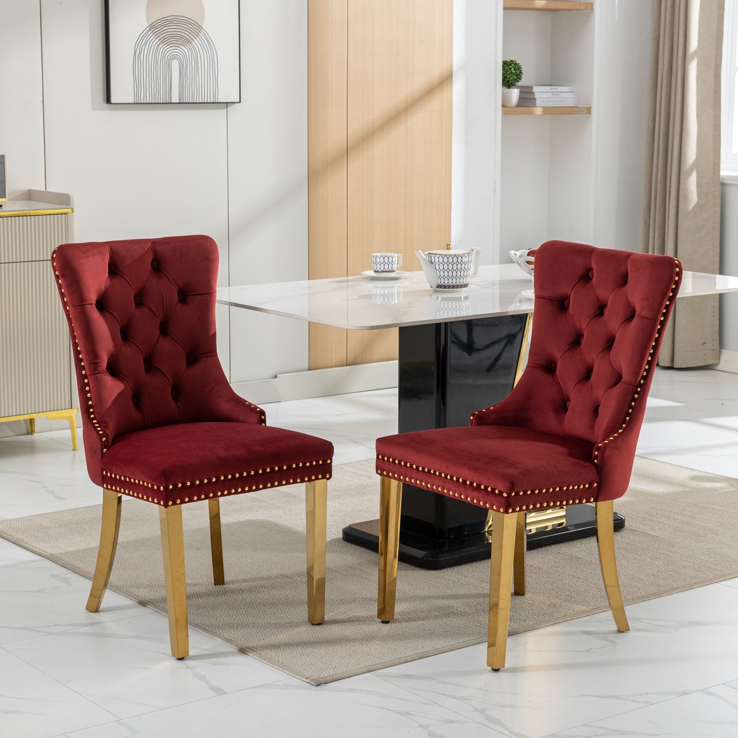 Two plush red velvet dining chairs with gold accents and tufted backs